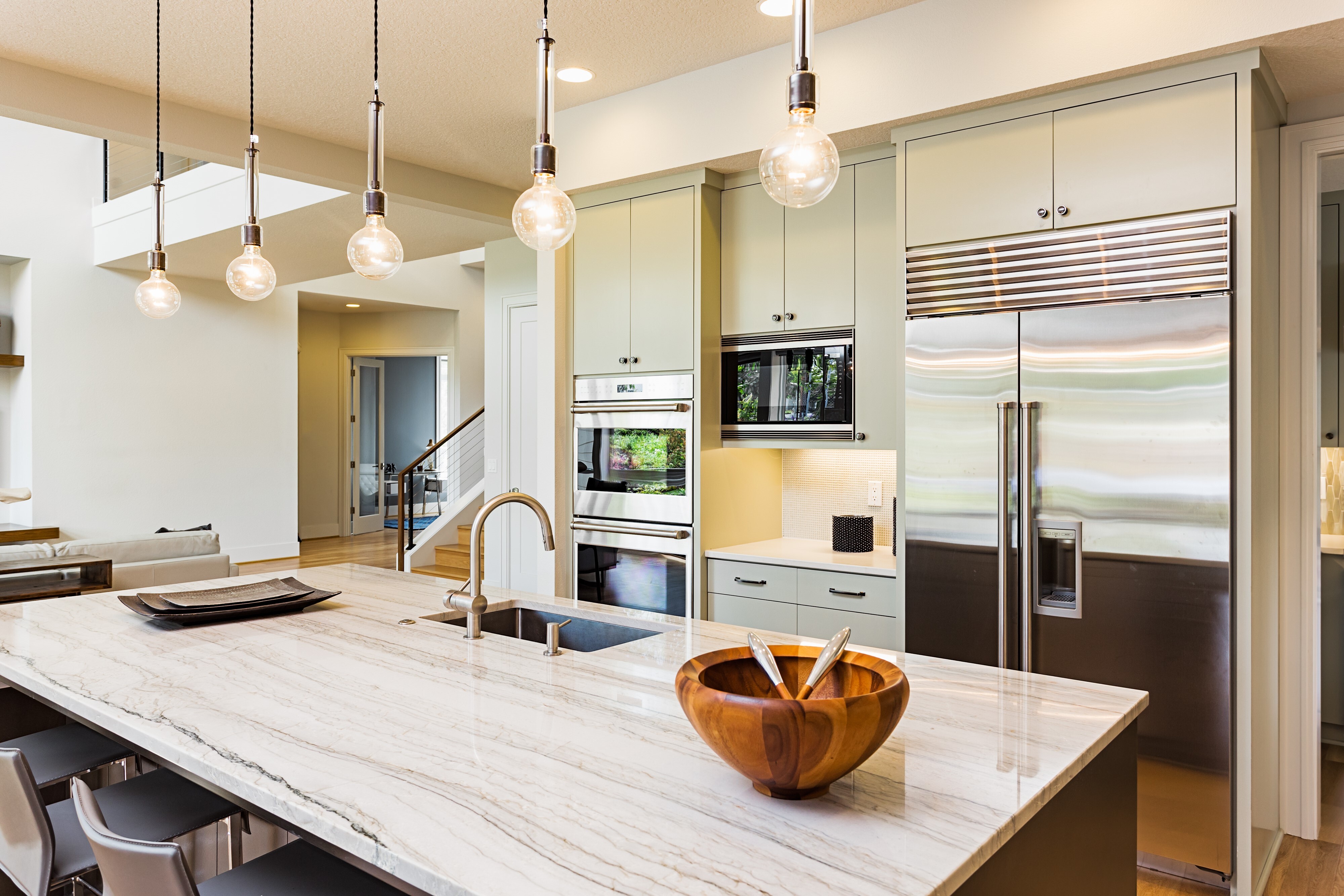 A kitchen island with a sink in the center of the shot